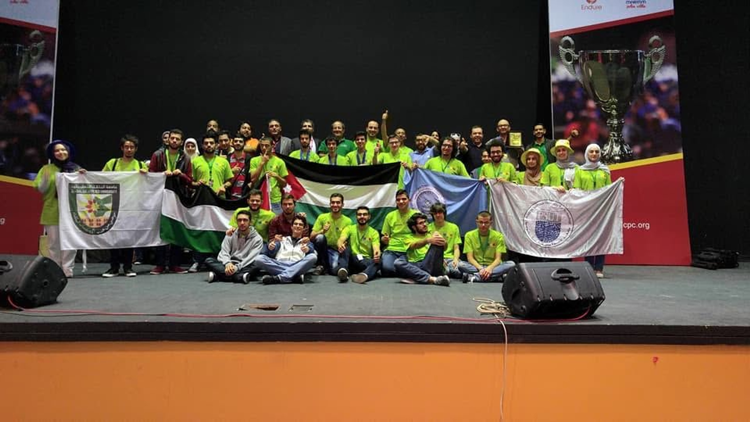 JCPC group photo on stage with the Jordanian flag