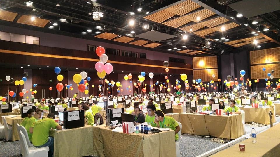 JCPC competition floor with colorful problem-solved balloons above teams