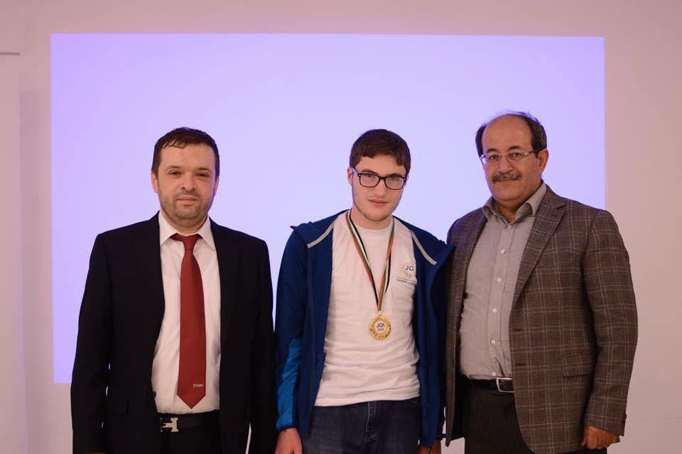 JOI medal winner with coaches at the awards stage