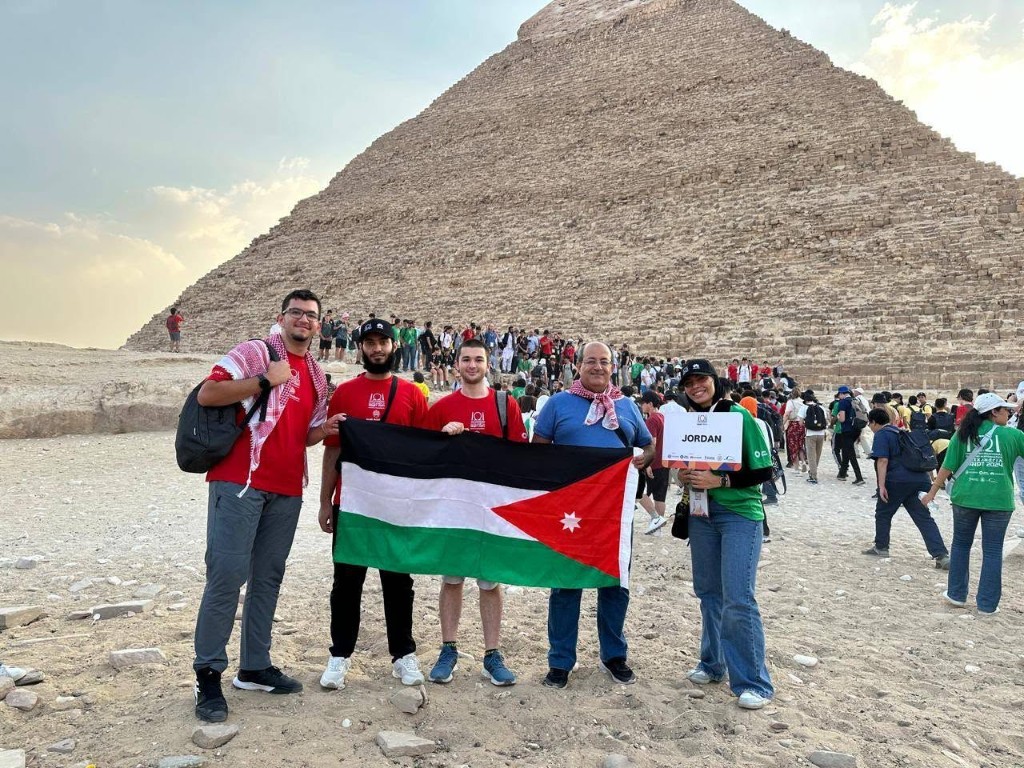 Jordan programming team photo with pyramids backdrop at an international event